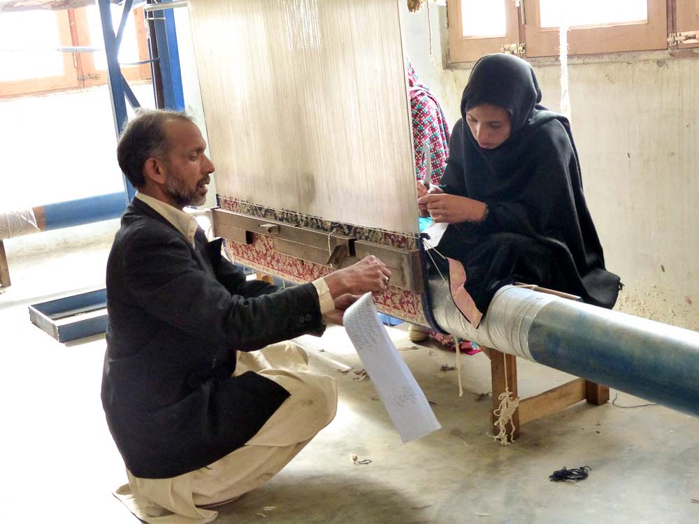 Haleem, rug instructor, working with Nadia on one of the 6 looms.