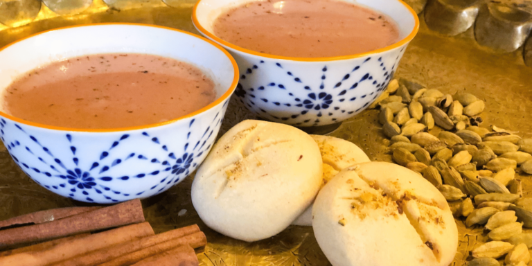 Two cups of kashmiri chai with nankhatai biscuits and spices